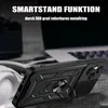A black phone case with a ring holder is shown in a close-up shot, with a blurred background of a laptop and headphones. Produktbild-Vorschau