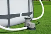 A pool filter pump connected to an above-ground pool, sitting on a grassy lawn. Produktbild-Vorschau