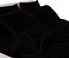 A close-up view of black bedding with red trim. Náhľad obrázku produktu