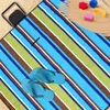 A striped beach blanket on sand with flip-flops and small toys. Produktbild-Vorschau
