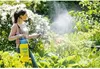 A woman is spraying plants in a garden with a pressure sprayer. Produktbild-Vorschau
