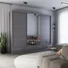 A modern gray sliding door wardrobe with mirrored panels is showcased in a living room setting, reflecting a sofa and part of the room. Voir les images du produit
