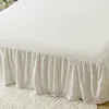 A close-up view of a white bed skirt with ruffles, draped over the side of a bed. Produktbild-Vorschau