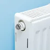A close-up shot of a white radiator valve against a light blue wall. Produktbild-Vorschau