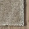 A close-up view of a beige rug with a high pile, placed on a wooden floor. Produktbild-Vorschau