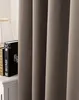 A close-up view of a taupe curtain, with two books and a lampshade visible on a white surface to the left. Produktbild-Vorschau