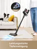 A person is using a cordless vacuum cleaner on a rug in a living room, with a dog on the couch. Produktbild-Vorschau