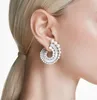 Close-up of a woman's ear wearing a spiral-shaped earring made of diamonds and pearls. Produktbild-Vorschau