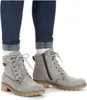 A pair of grey lace-up boots worn by a person wearing blue jeans and white socks. Anteprima dell’immagine prodotto