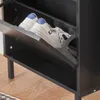 A close-up view of a black shoe cabinet with a drawer open, revealing a pair of white sneakers with blue accents. Produktbild-Vorschau