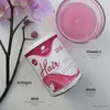 A product shot of a hair vitamin supplement container, with a glass of pink liquid and an orchid flower. Produktbild-Vorschau
