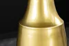 A close-up shot of a gold-colored metal table base with a brushed finish and patina. Produktbild-Vorschau