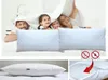 A family is playfully hiding under a duvet, with pillows in the foreground. Smaller images show a single pillow and a close-up of its filling. Produktbild-Vorschau