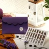 A flat lay of knitting supplies including a purple pouch, knitting needles, yarn, and a decorative lantern. Produktbild-Vorschau
