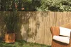 A bamboo fence in a garden with a potted plant and a chair. Produktbild-Vorschau