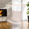 A hammock chair is shown hanging in a living room with a fireplace and large windows. Produktbild-Vorschau
