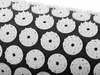 A close-up, angled view of a black acupressure mat with many white circular acupressure points. Podgląd zdjęcia produktu