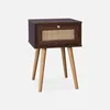A dark wood bedside table with a rattan drawer front and light wood legs, set against a white background. Produktbild-Vorschau