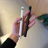 A hand holding two cable organizers, one white and one black. Produktbild-Vorschau