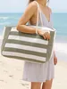 A woman on a beach holding a striped beach bag. Produktbild-Vorschau