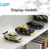 Three toy race cars are displayed on a white shelf, with books visible in the background. Anteprima dell’immagine prodotto