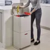 A person is shown discarding banana peels into a multi-compartment kitchen bin. Podgląd zdjęcia produktu