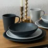 A table setting with mugs, bowls, and plates, along with a candlestick. Produktbild-Vorschau