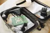 A suitcase packed with travel essentials including a garment steamer, hat, book, sunglasses, and a vintage camera. Voir les images du produit