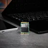 A small SSD is placed on a textured surface next to a laptop and a smartphone. Anteprima dell’immagine prodotto