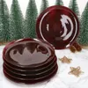 A stack of red plates in the foreground with a single plate behind it, surrounded by miniature Christmas trees and pinecones. Produktbild-Vorschau