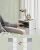 A person is placing a phone into a compartment of a white side table next to a chair. Below is a diagram illustrating the orientation of the furniture. Náhled obrázku produktu