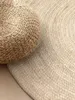 A close-up view of a round jute rug and a round jute pouf. Anteprima dell’immagine prodotto