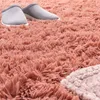A close-up view of a fluffy pink rug with a pair of gray slippers on it. Produktbild-Vorschau