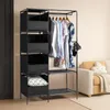 A black fabric wardrobe with shelves and a hanging rod, displaying several pieces of clothing and a pillow. A yellow sofa with a cloud-shaped pillow is visible in the background. Produktbild-Vorschau
