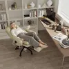 A woman is relaxing in a beige ergonomic office chair with an extended footrest in a home office setting. Náhled obrázku produktu