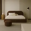 A modern bedroom with a brown upholstered bed, bedside table, and floor lamp. Voir les images du produit