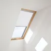 A skylight window with a white roller blind partially covering it, set against a white sloped ceiling. Produktbild-Vorschau