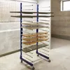 A drying rack with multiple shelves holding various wooden and metal panels, possibly in a workshop or storage area. Voir les images du produit