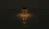 A decorative lantern casting intricate shadows on a dark surface. Produktbild-Vorschau