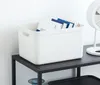 A white storage box filled with books sits on a black shelf. Produktbild-Vorschau