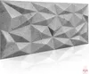 A 3D geometric wall panel with a concrete texture, shown in a studio setting with a reflective surface below. Produktbild-Vorschau