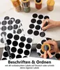 Schwarze kreisförmige Tafelettiketten und ein weißer Kreidestift, mit einer Hand, die 'BBQ' auf ein Etikett schreibt, das auf einem Gewürzglasdeckel angebracht ist Voir les images du produit