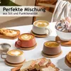 A collection of cappuccino cups with latte art, along with bread and pastries, arranged on a table. Produktbild-Vorschau