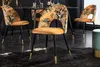 Dining chairs with a floral pattern and gold accents are arranged around a dining table in a modern setting. Produktbild-Vorschau