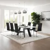 A modern dining room with a white dining table and black chairs, illuminated by pendant lights. Voir les images du produit