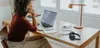 A woman is working on her laptop at a desk with a lamp and headphones. Náhled obrázku produktu