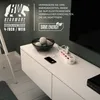 A white power strip with red outlets is plugged into the wall, charging a smartphone. A bowl of decorative balls sits on a white cabinet. Voir les images du produit