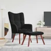 A black velvet armchair and ottoman are placed on a rug in a living room setting. Produktbild-Vorschau
