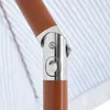 Close-up of a joint mechanism on a brown umbrella pole, with a blue and white striped fabric in the background. Produktbild-Vorschau