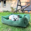 A French Bulldog lies in a green dog bed on a grassy lawn. Náhled obrázku produktu